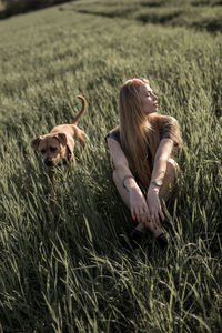 Young woman with dog sitting on grassy field