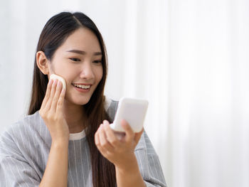 Portrait of smiling young woman using mobile phone