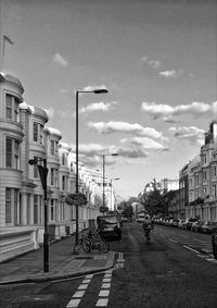 Cars on street in city against sky
