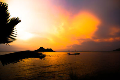 Silhouette boats in calm sea at sunset