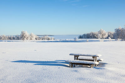 Scenic view of snow covered field against clear blue sky