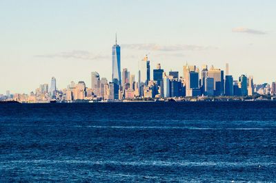 Sea and buildings in city against sky