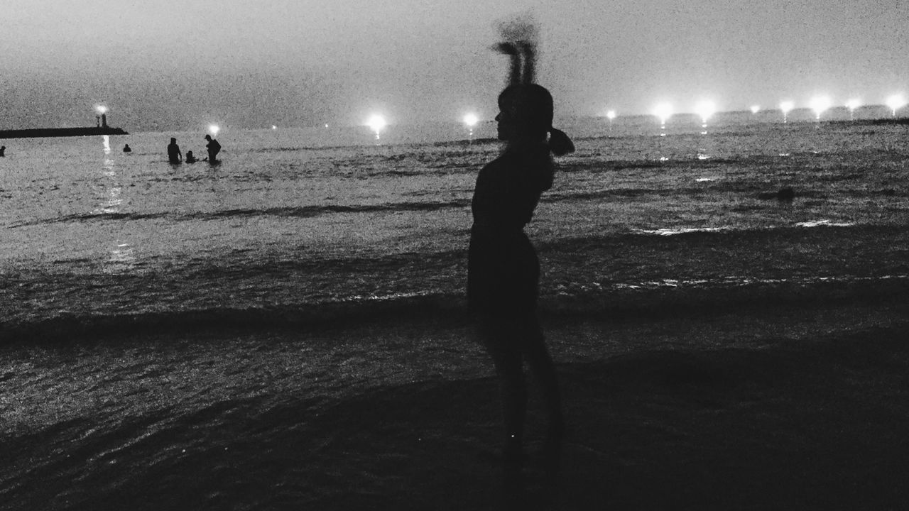 SILHOUETTE WOMAN STANDING ON BEACH AGAINST SKY