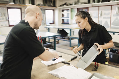 Male teacher assisting high school student on project in class