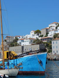 Man standing on boat moored at harbor against sky