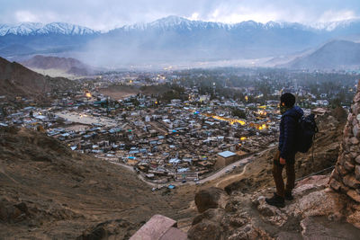 Rear view of man standing on landscape against mountains