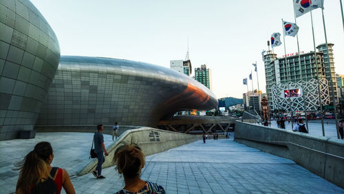 People in modern building against clear sky