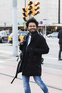 Portrait of young man standing on road in city