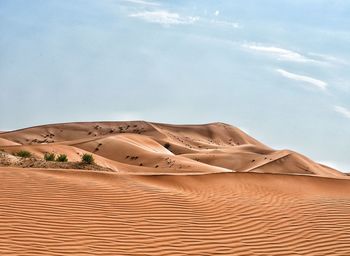 Sand dunes in desert against sky