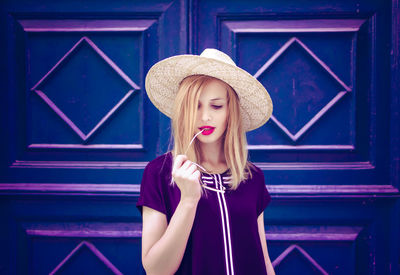 Portrait of beautiful young woman standing against blue wall