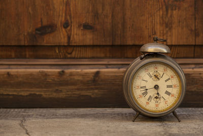 Close-up of old alarm clock against wood