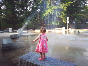 Rear view of girl standing against pink and trees