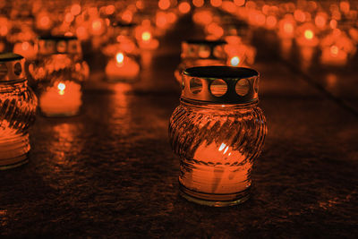 Burning church candles in red transparent chandeliers