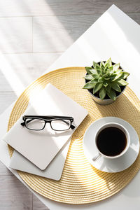 Office desk with coffee cup, succulent plant, eyeglasses and notepad. 