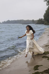 Full length of woman at beach against sky