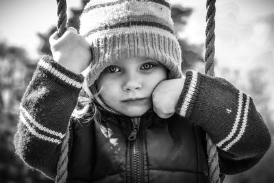 Portrait of cute girl wearing hat sitting on swing