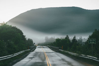 Road amidst trees against sky during rainy season