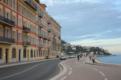 Road by buildings in city against sky