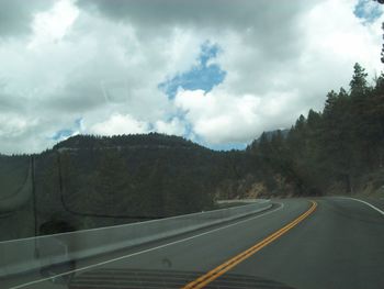 Road by trees against sky