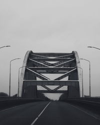 Empty road against bridge against sky