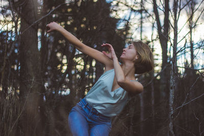 Midsection of woman with arms raised in forest