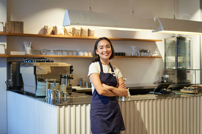 Portrait of young woman standing in kitchen