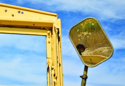 Low angle view of yellow machinery against sky