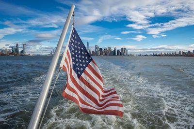 Flag on sea by city against sky