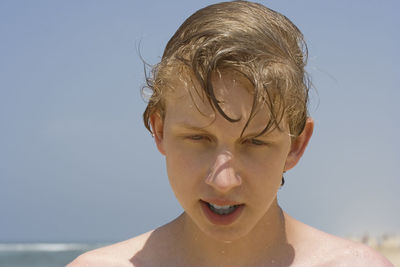 Close-up of wet teenage boy at beach against sky