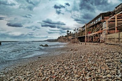 Buildings at beach against cloudy sky