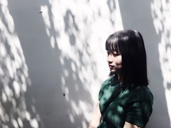 Young woman standing against white wall