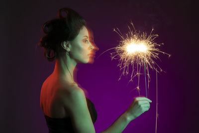 Blurred motion of woman holding illuminated sparkler at night