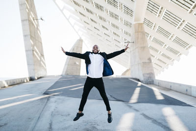 Full length of man with arms outstretched standing in city