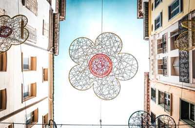 Flower installation between houses, framed against a clear blue sky. 