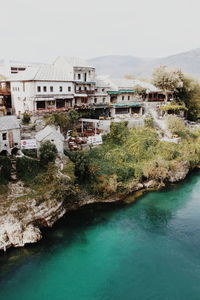 Buildings by river in town against clear sky