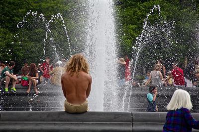 Rear view of people enjoying in fountain 