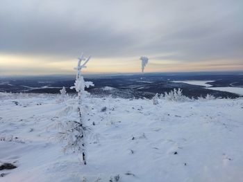 Snow covered land against sky during sunset