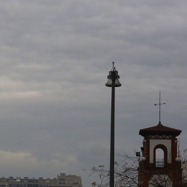 sky, building exterior, architecture, built structure, low angle view, cloud - sky, cloudy, religion, church, place of worship, cross, street light, spirituality, cloud, weather, lighting equipment, high section, overcast