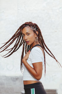 Portrait of young woman with braided hair standing against wall