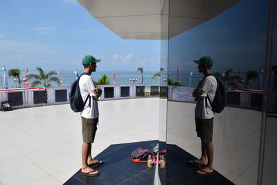 Rear view of friends standing on boat against sky