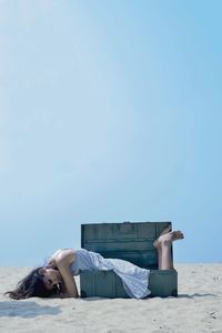 Woman relaxing against blue sky