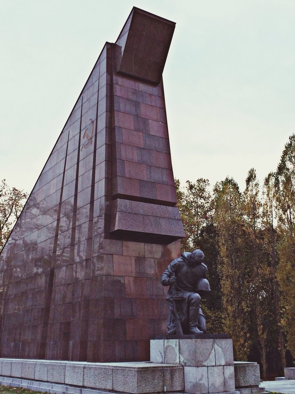 statue, architecture, sculpture, human representation, built structure, art and craft, art, building exterior, low angle view, creativity, history, clear sky, tree, sky, stone material, carving - craft product, famous place, monument, travel destinations