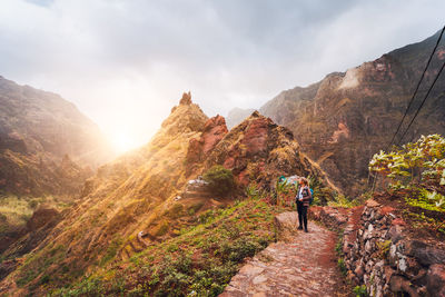 Woman looking at view while standing against mountain during sunrise