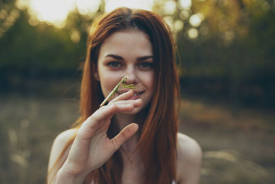 Close-up portrait of young woman holding grasshopper
