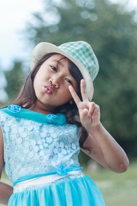 Portrait of cute girl wearing hat gesturing while standing outdoors