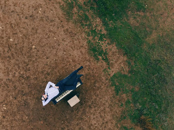 Pianist woman in sunglasses lies on a piano on a mountain by the sea in spring. dron