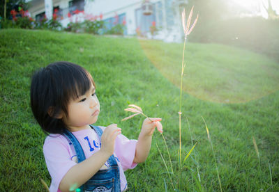 Cute girl holding plant on grassy field