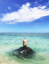 Man sitting in sea against sky