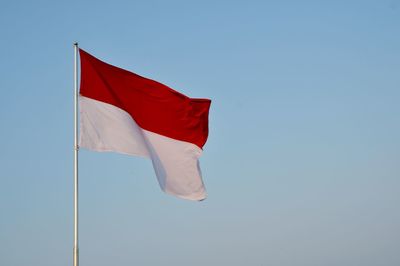 Low angle view of indonesian flag against clear blue sky