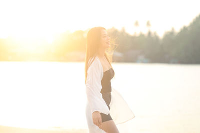 Side view of woman standing against sky during sunset